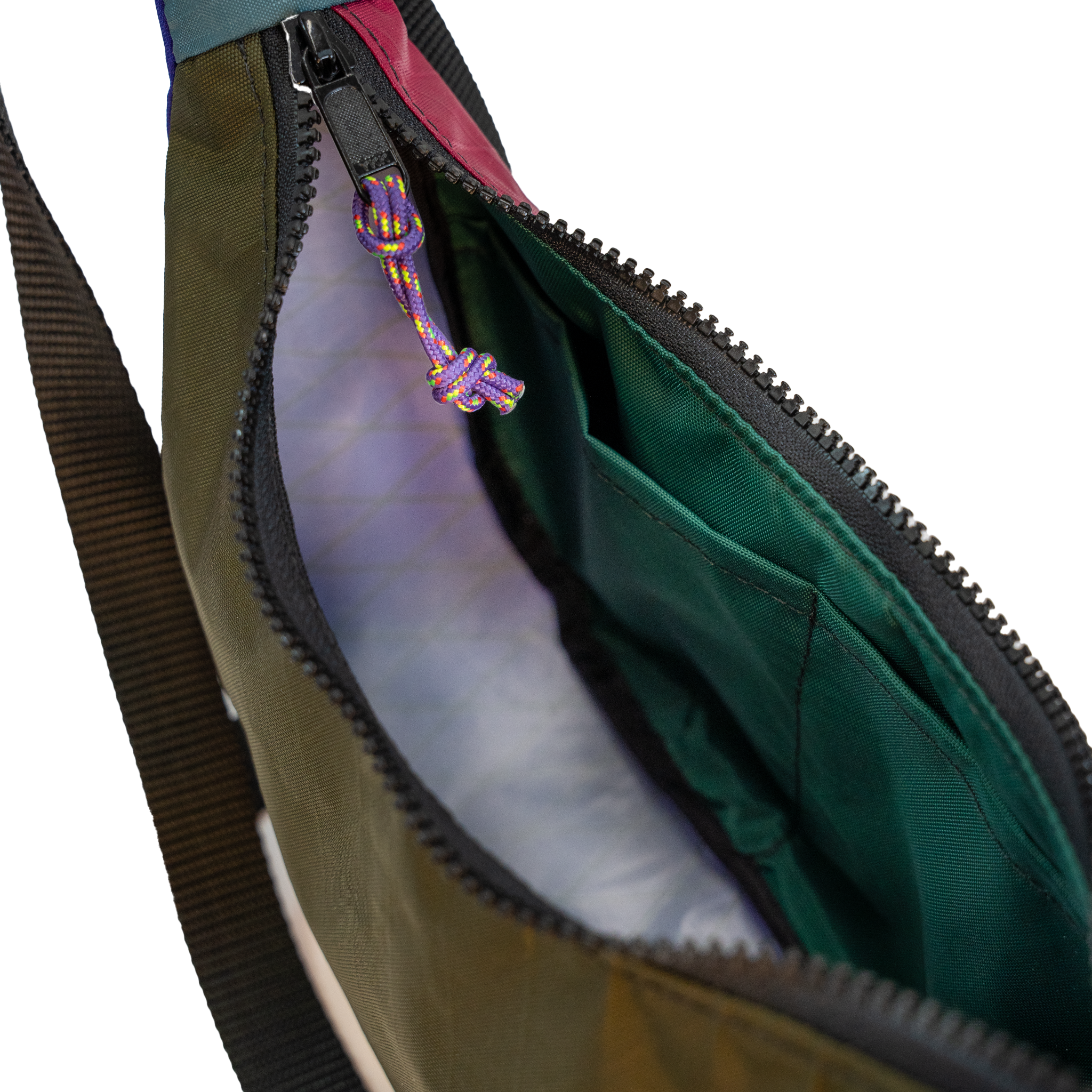 Close-up of an open bag showing the interior, with an olive green exterior, dark green lining, black zipper, and a purple-and-yellow knotted zipper pull on a white background.